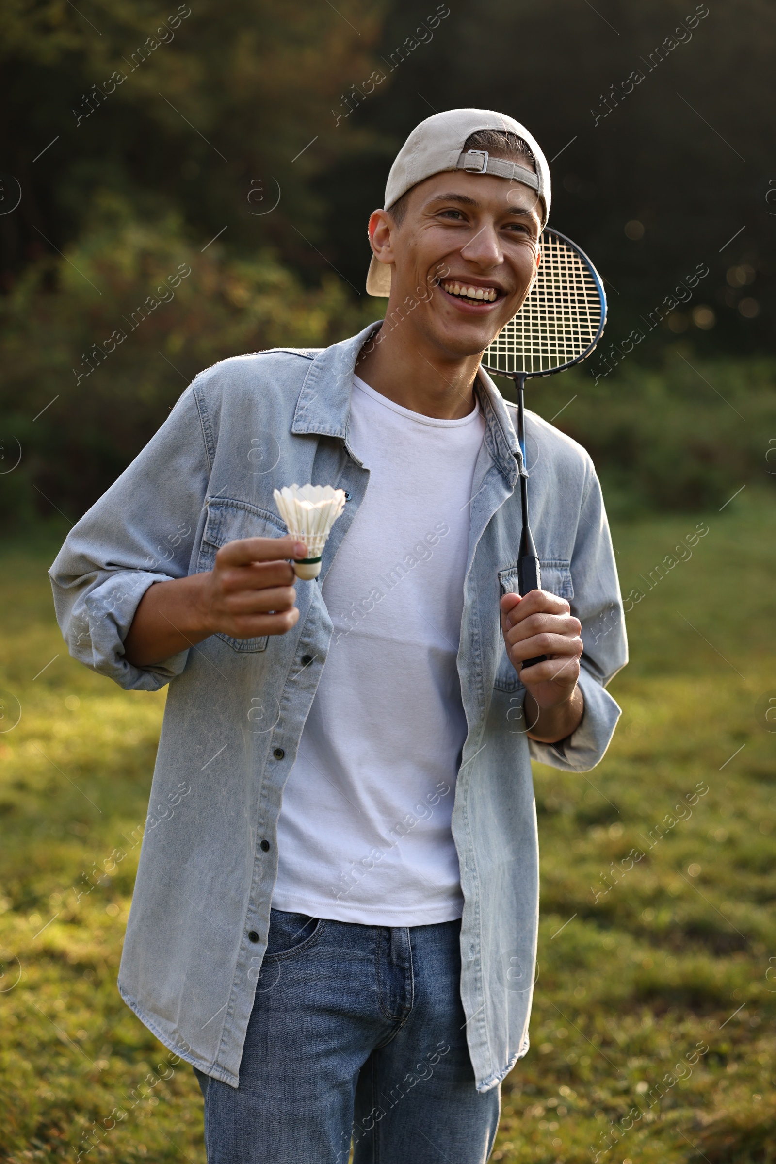 Photo of Happy young man with badminton racket and shuttlecock in park