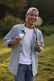 Happy young man with badminton racket and shuttlecock in park