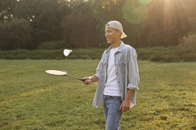 Young man playing badminton racket in park on sunny day