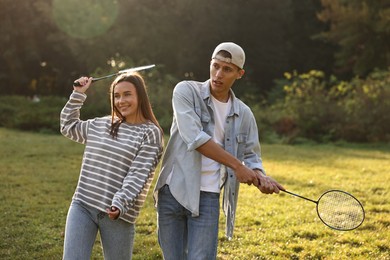 Young woman and man playing badminton in park on sunny day