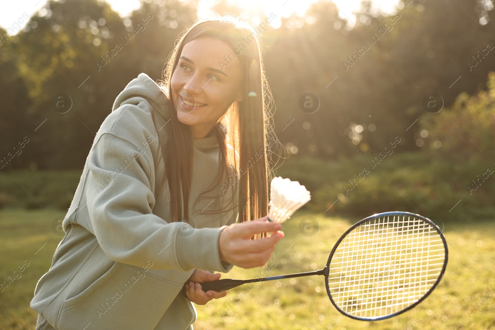 Photo of Happy young woman playing badminton racket in park on sunny day