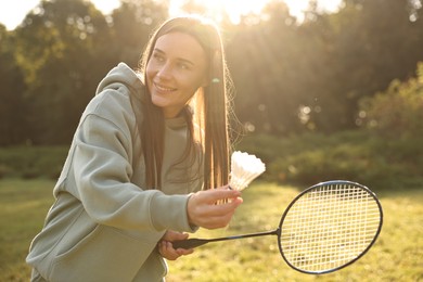 Photo of Happy young woman playing badminton racket in park on sunny day