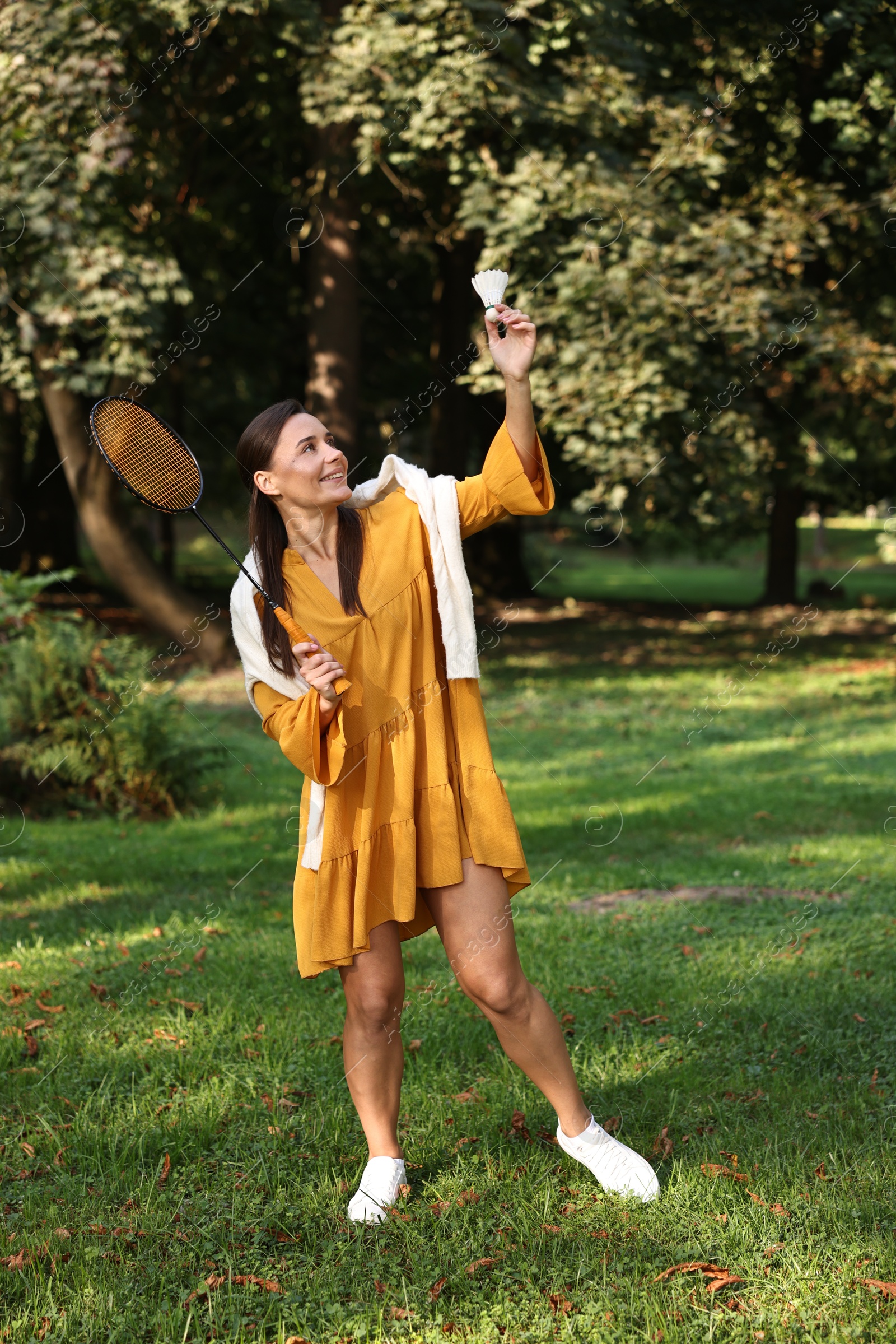 Photo of Happy young woman playing badminton racket in park