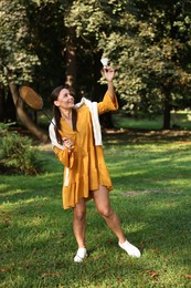 Photo of Happy young woman playing badminton racket in park