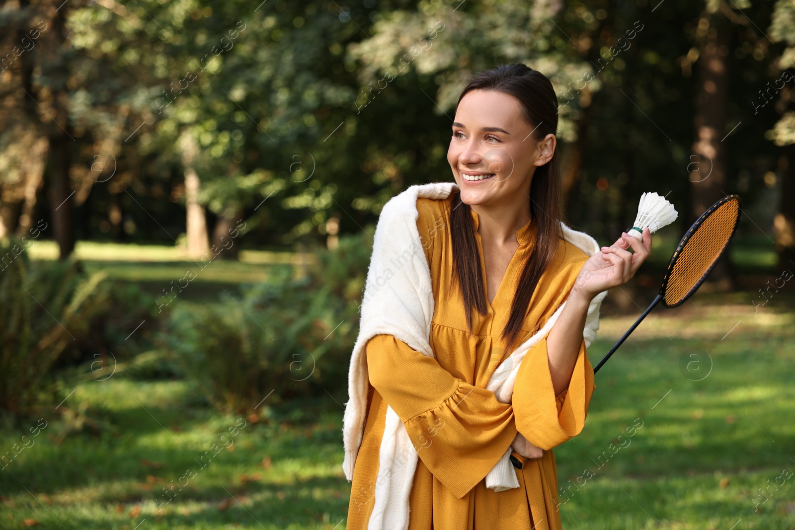 Photo of Happy young woman with badminton racket and shuttlecock in park