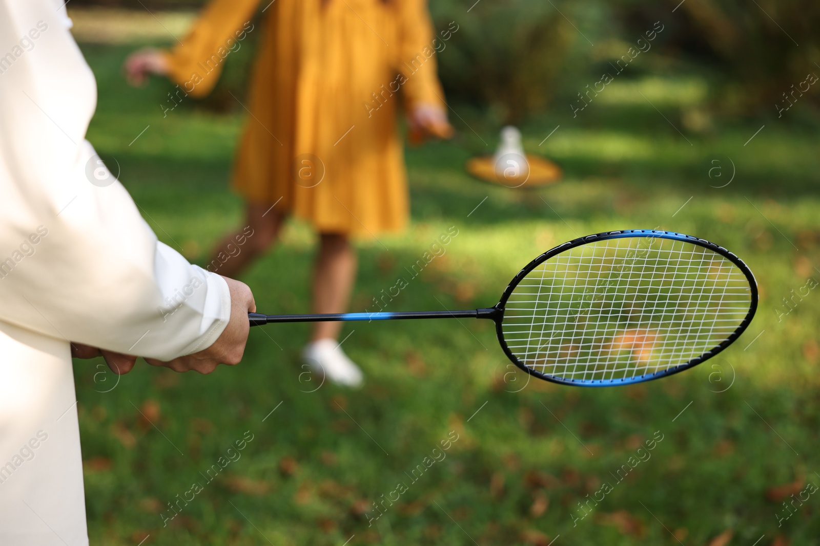 Photo of Young man and woman playing badminton in park, closeup