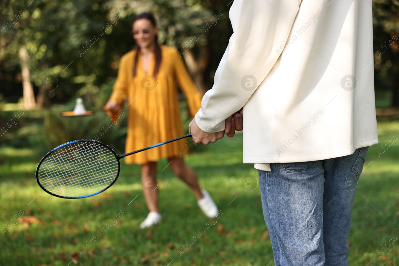 Photo of Young woman and man playing badminton in park, selective focus