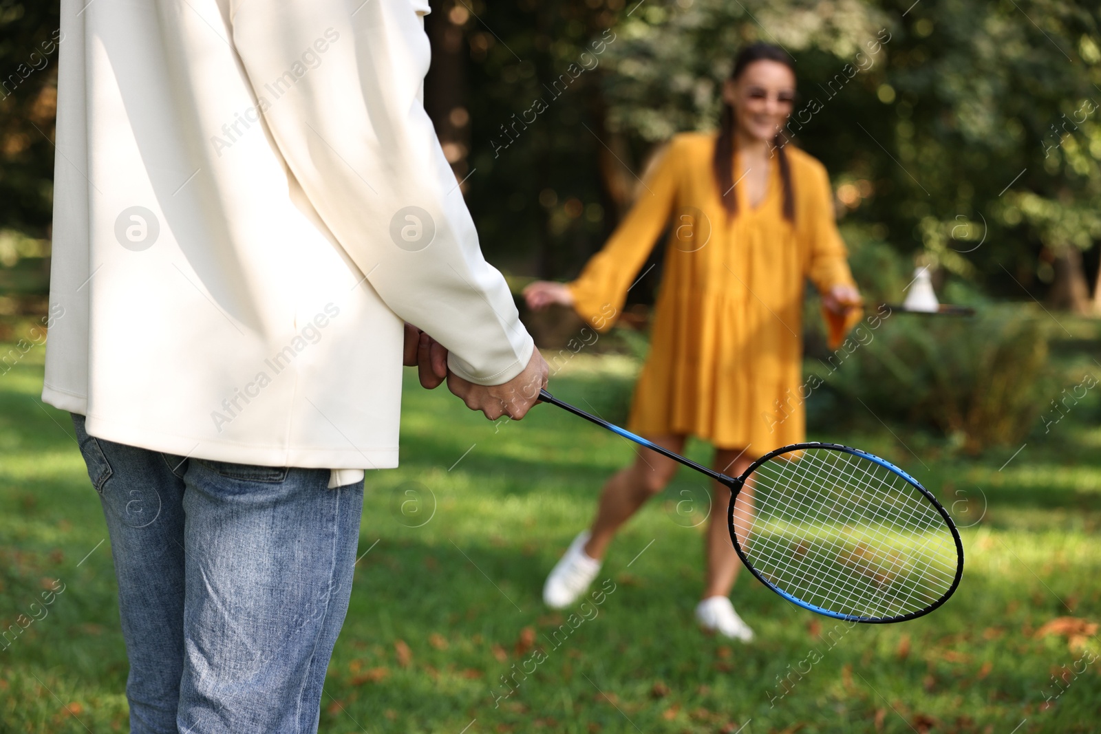 Photo of Young woman and man playing badminton in park, selective focus