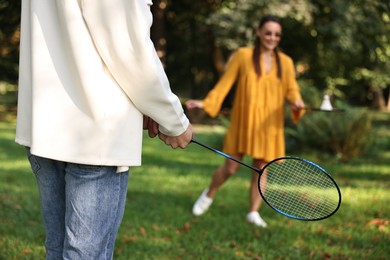 Photo of Young woman and man playing badminton in park, selective focus