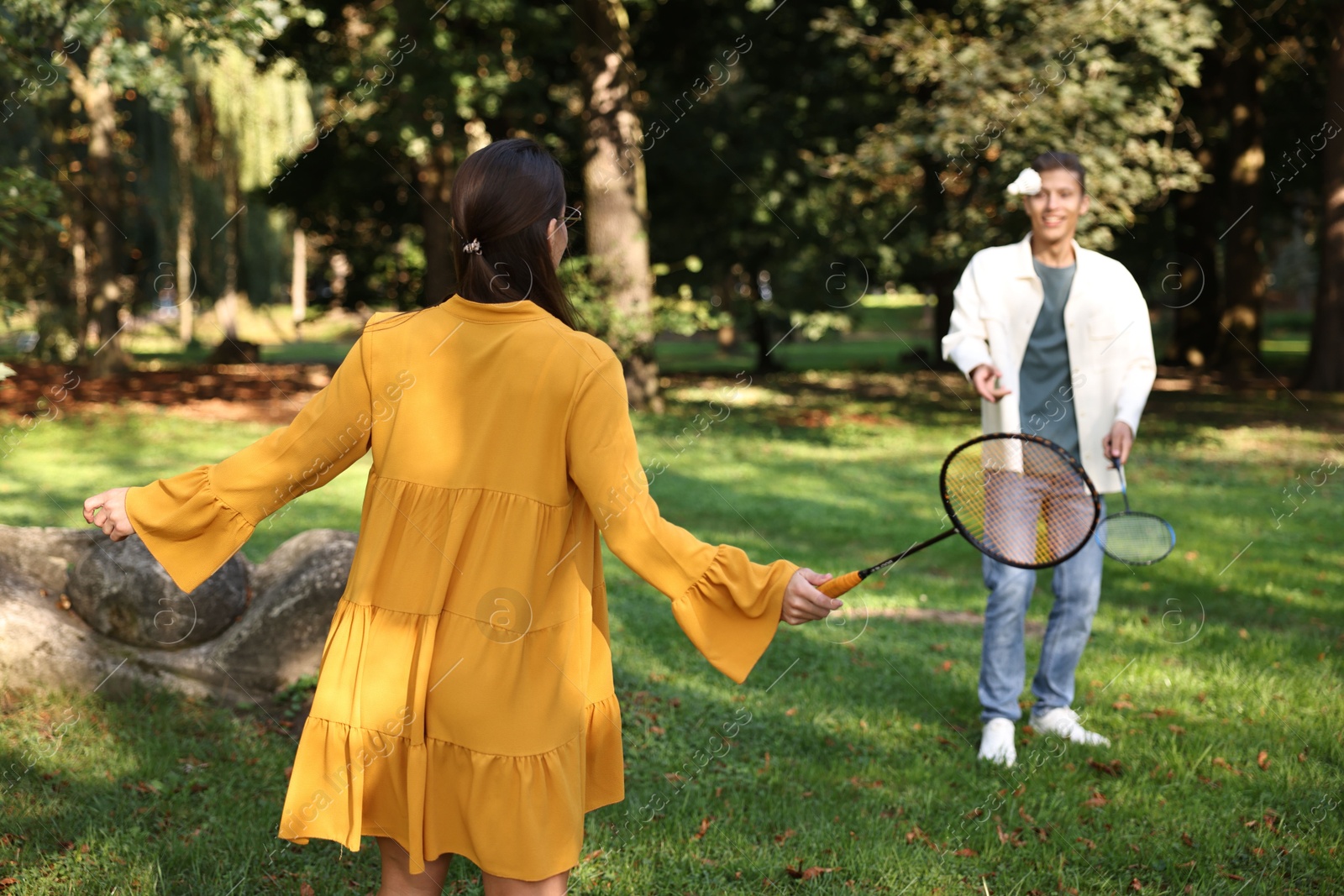 Photo of Young woman and man playing badminton in park, selective focus