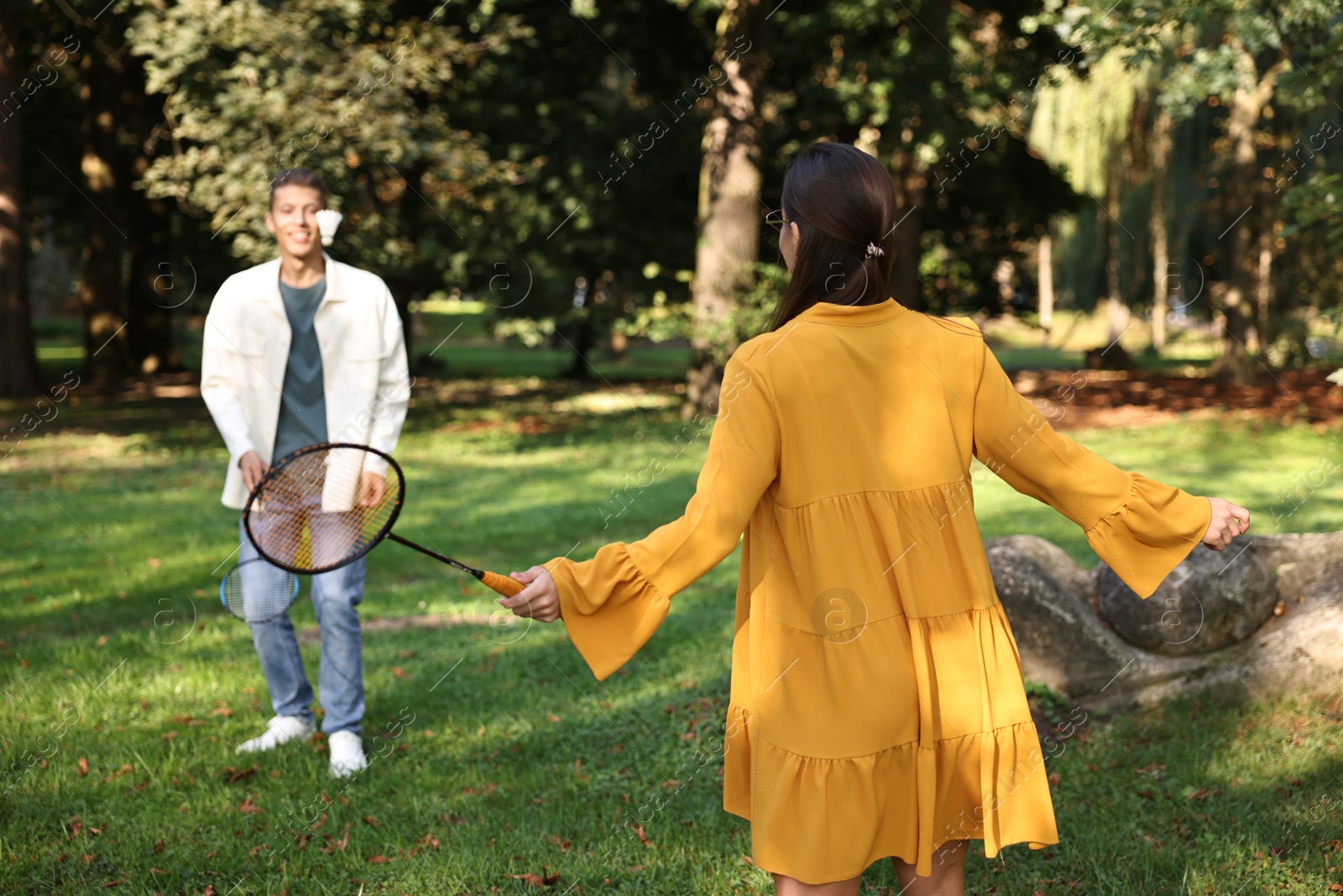 Photo of Young woman and man playing badminton in park, selective focus