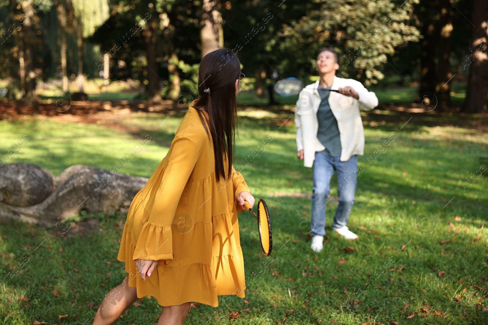 Photo of Young woman and man playing badminton in park, selective focus