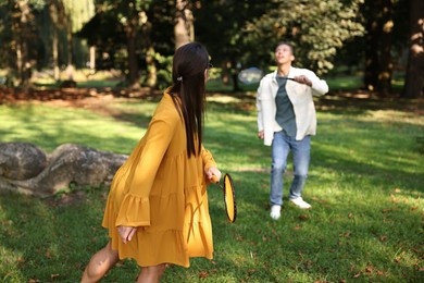 Photo of Young woman and man playing badminton in park, selective focus