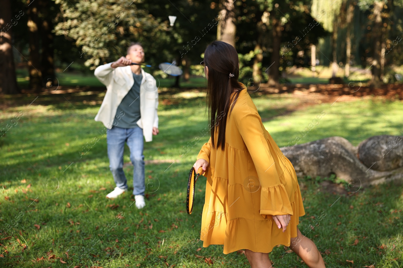 Photo of Young woman and man playing badminton in park, selective focus