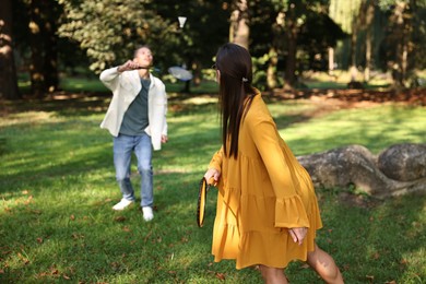 Young woman and man playing badminton in park, selective focus