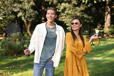 Young man and woman with badminton rackets and shuttlecock in park