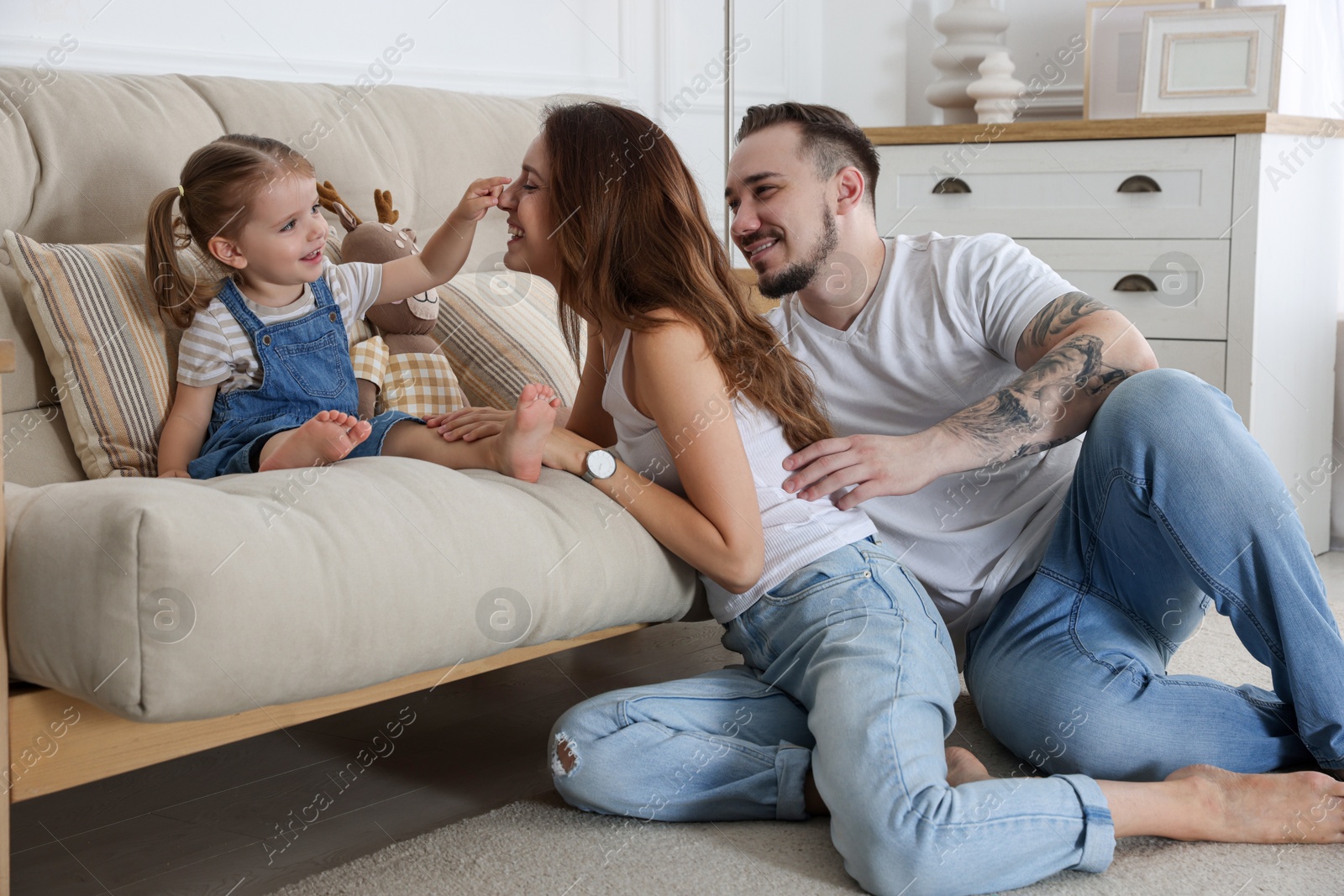 Photo of Happy family. Parents and their cute little daughter on sofa at home