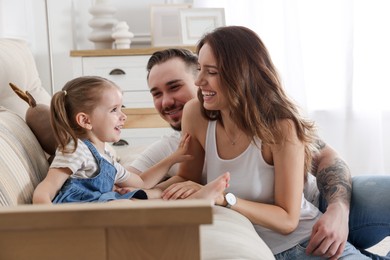 Happy family. Parents and their cute little daughter on sofa at home