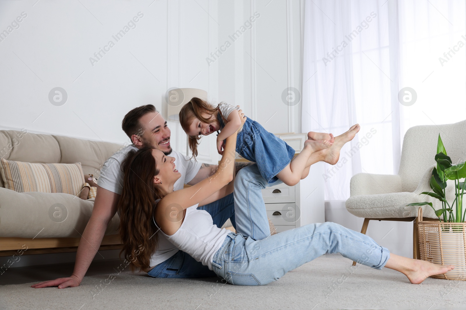 Photo of Happy family. Parents and their cute little daughter having fun at home