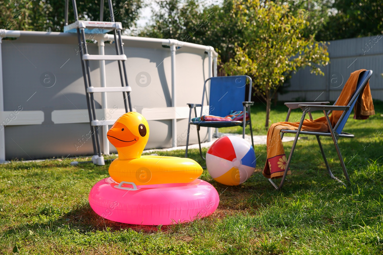 Photo of Above ground swimming pool, folding chairs, towel, inflatable rings and ball in backyard