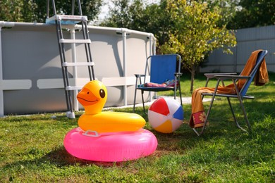 Above ground swimming pool, folding chairs, towel, inflatable rings and ball in backyard