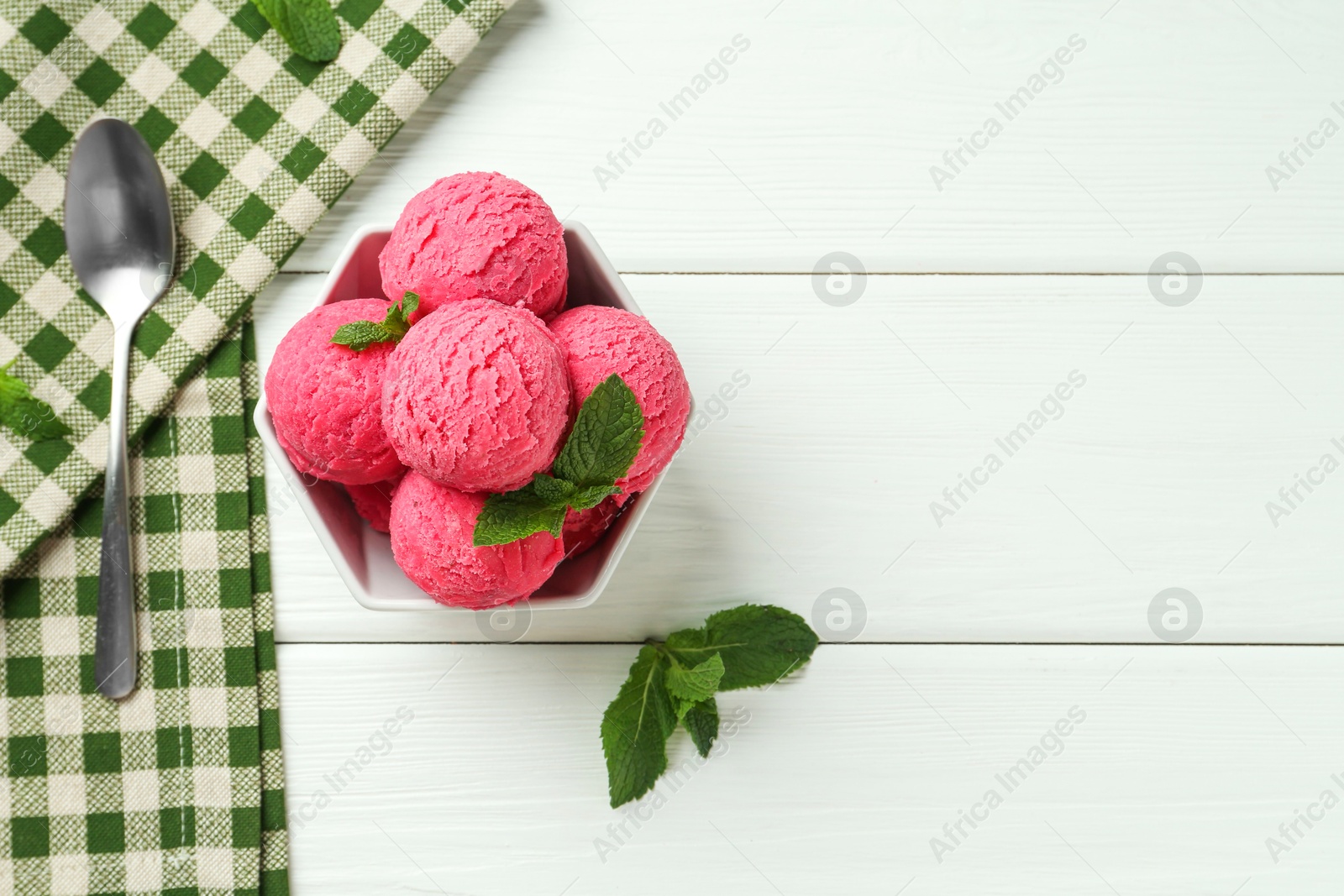 Photo of Scoops of tasty watermelon sorbet with mint in bowl and spoon on white wooden table, flat lay. Space for text