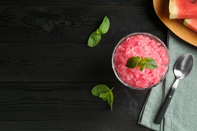 Photo of Tasty watermelon sorbet with mint in glass dessert bowl and spoon on black wooden table, flat lay. Space for text