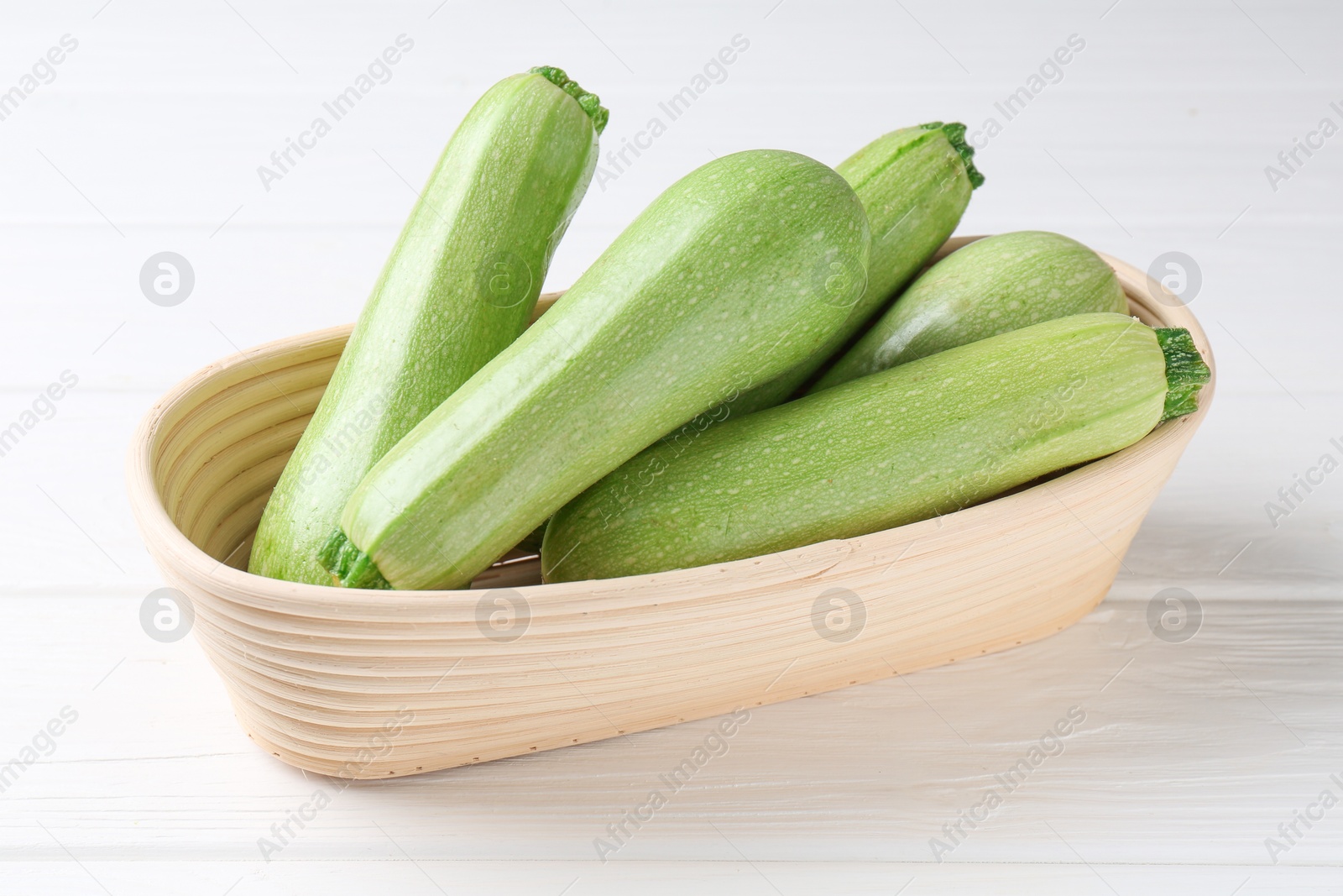 Photo of Fresh ripe zucchinis on white wooden table, closeup