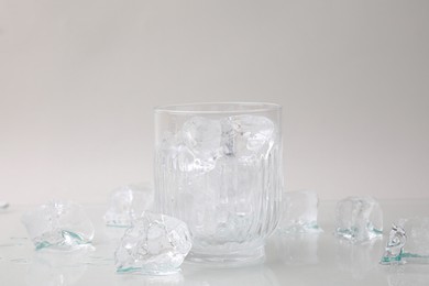 Photo of Refreshing water in glass with ice cubes on light background