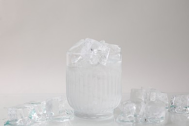 Photo of Refreshing water in glass with ice cubes on light background