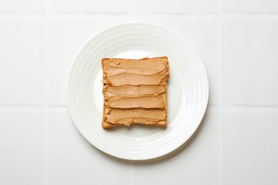 Photo of Delicious sandwich with peanut butter on white tiled table, top view