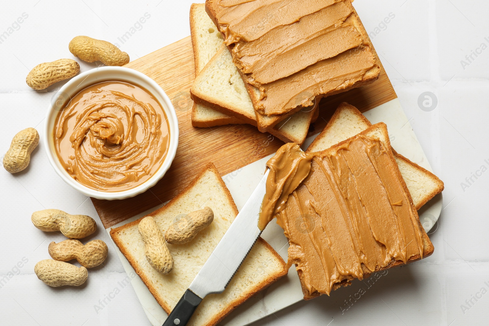 Photo of Delicious sandwiches with peanut butter and fresh nuts on white table, top view