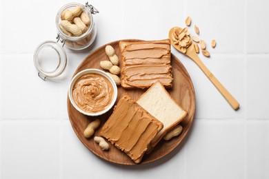 Photo of Delicious sandwiches with peanut butter and fresh nuts on white table, flat lay