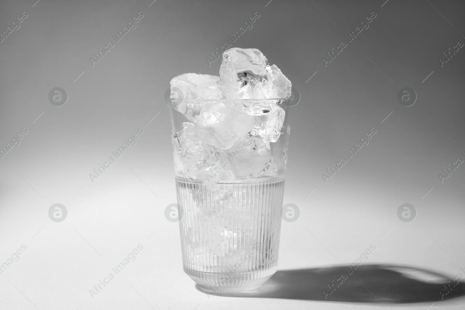 Photo of Refreshing water with ice in glass on grey background