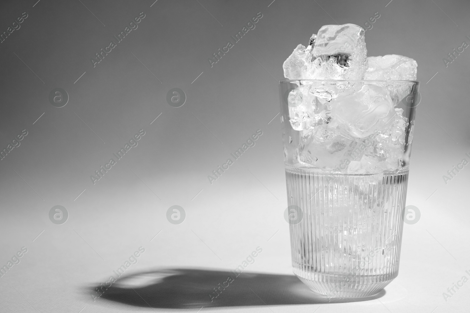 Photo of Refreshing water with ice in glass on grey background. Space for text