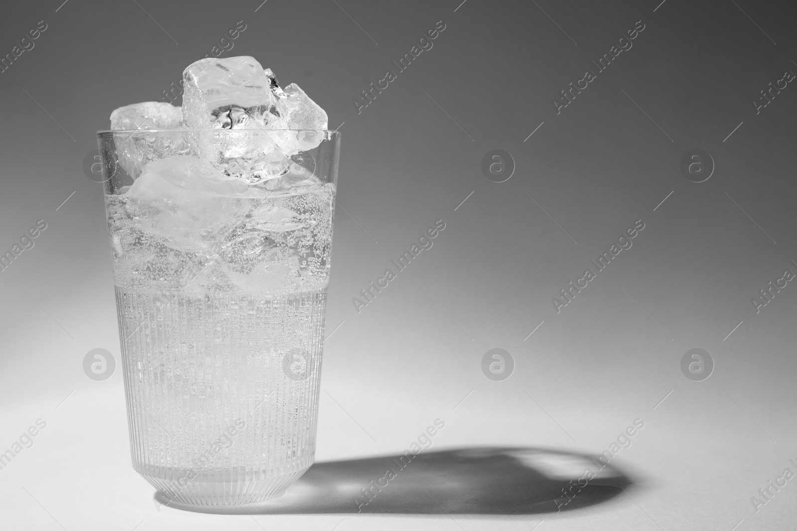 Photo of Refreshing water with ice in glass on grey background. Space for text