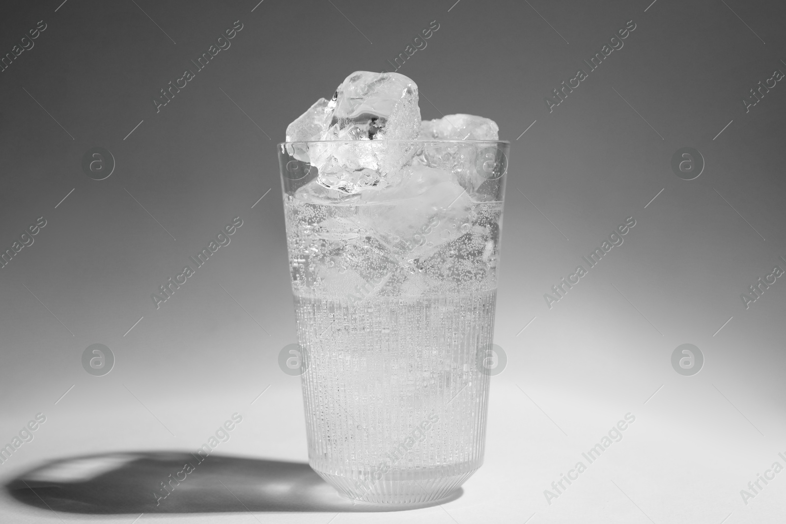 Photo of Refreshing water with ice in glass on grey background