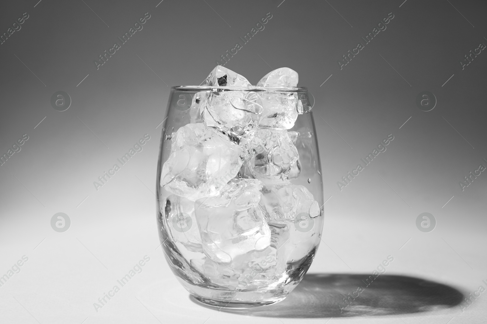 Photo of One glass with ice for refreshing drink on grey background