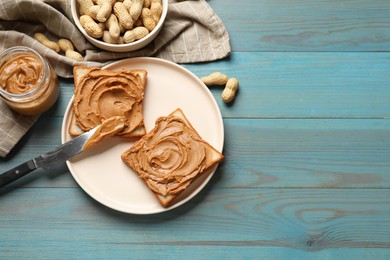 Photo of Tasty sandwiches with peanut butter and nuts on light blue wooden table, flat lay. Space for text