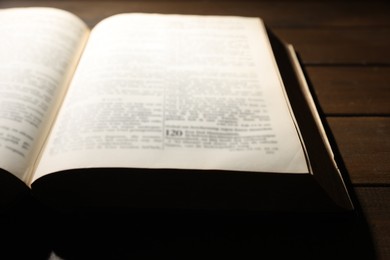 Photo of Open Bible on wooden table, closeup. Christian faith