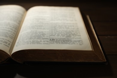 Photo of Open Bible on wooden table, closeup. Christian faith