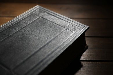 Photo of Closed Bible on wooden table, closeup. Christian faith