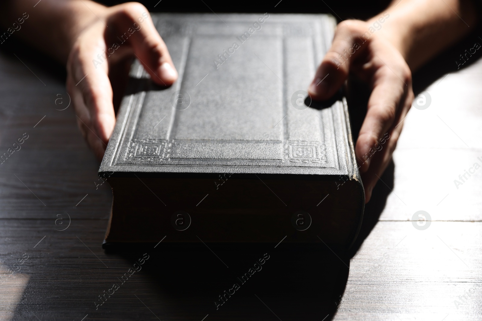 Photo of Man with Bible at wooden table, closeup