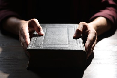 Photo of Man with Bible at wooden table, closeup