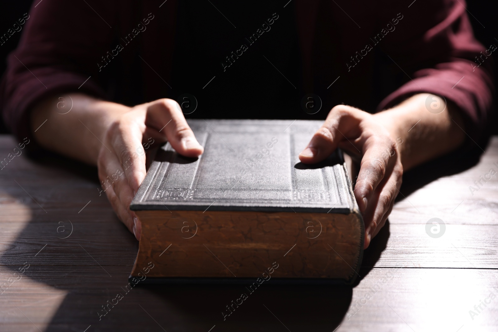 Photo of Man with Bible at wooden table, closeup