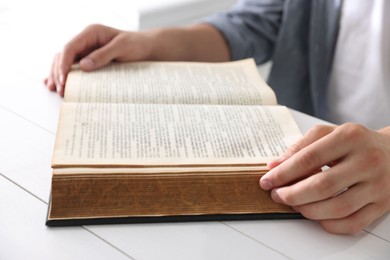 Photo of Man with Bible at white wooden table, closeup