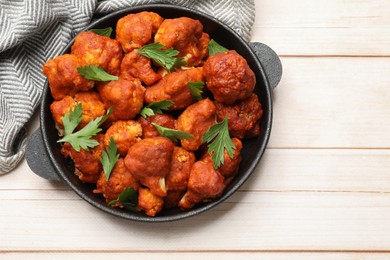 Photo of Baked cauliflower buffalo wings with parsley in baking dish on wooden table, top view