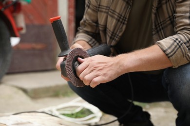 Photo of Man with angle grinder outdoors, closeup view