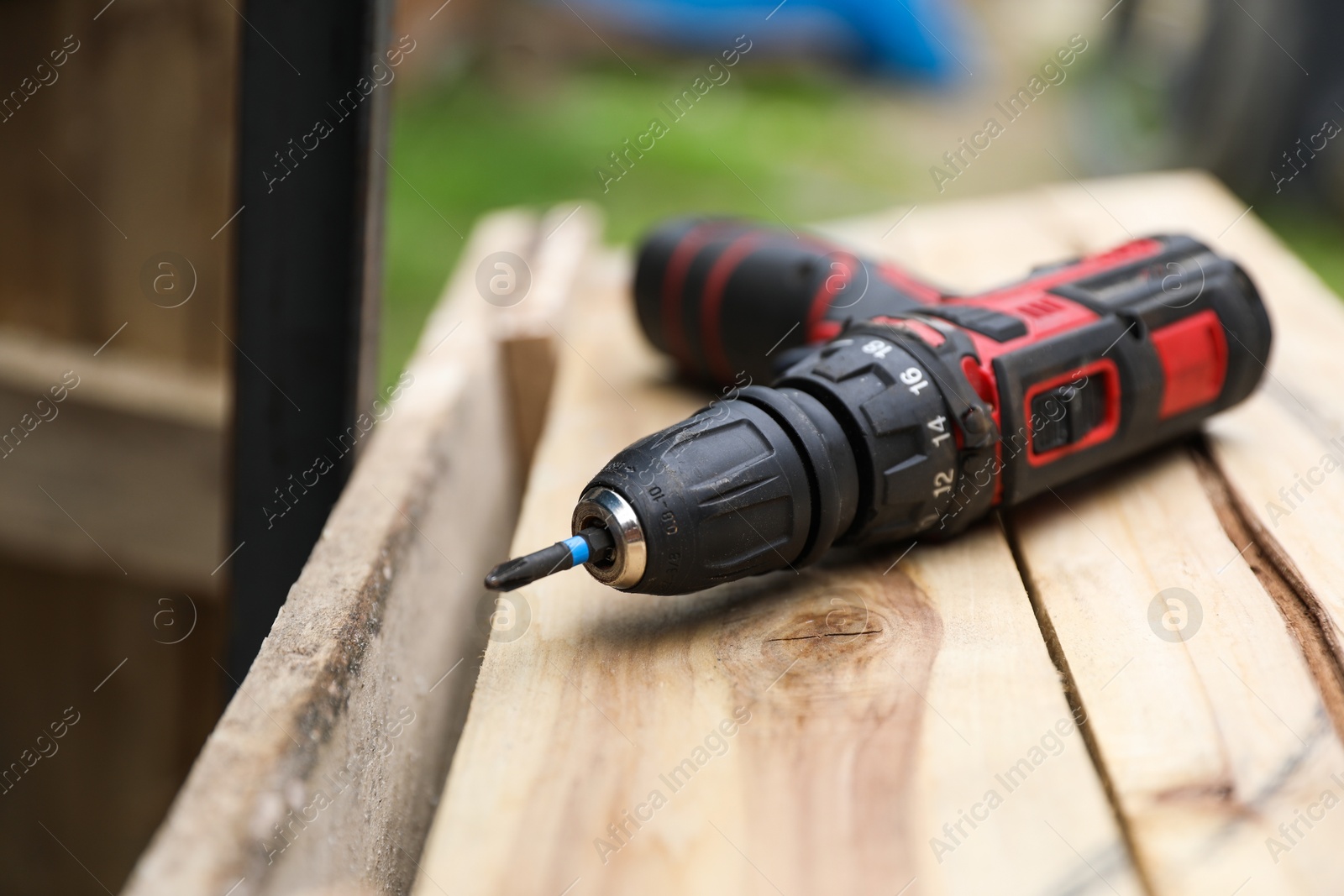 Photo of Electric screwdriver on wooden plank outdoors, closeup