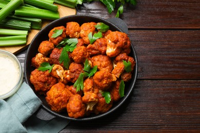 Photo of Tasty cauliflower buffalo wings, sauce and celery on wooden table, flat lay. Space for text